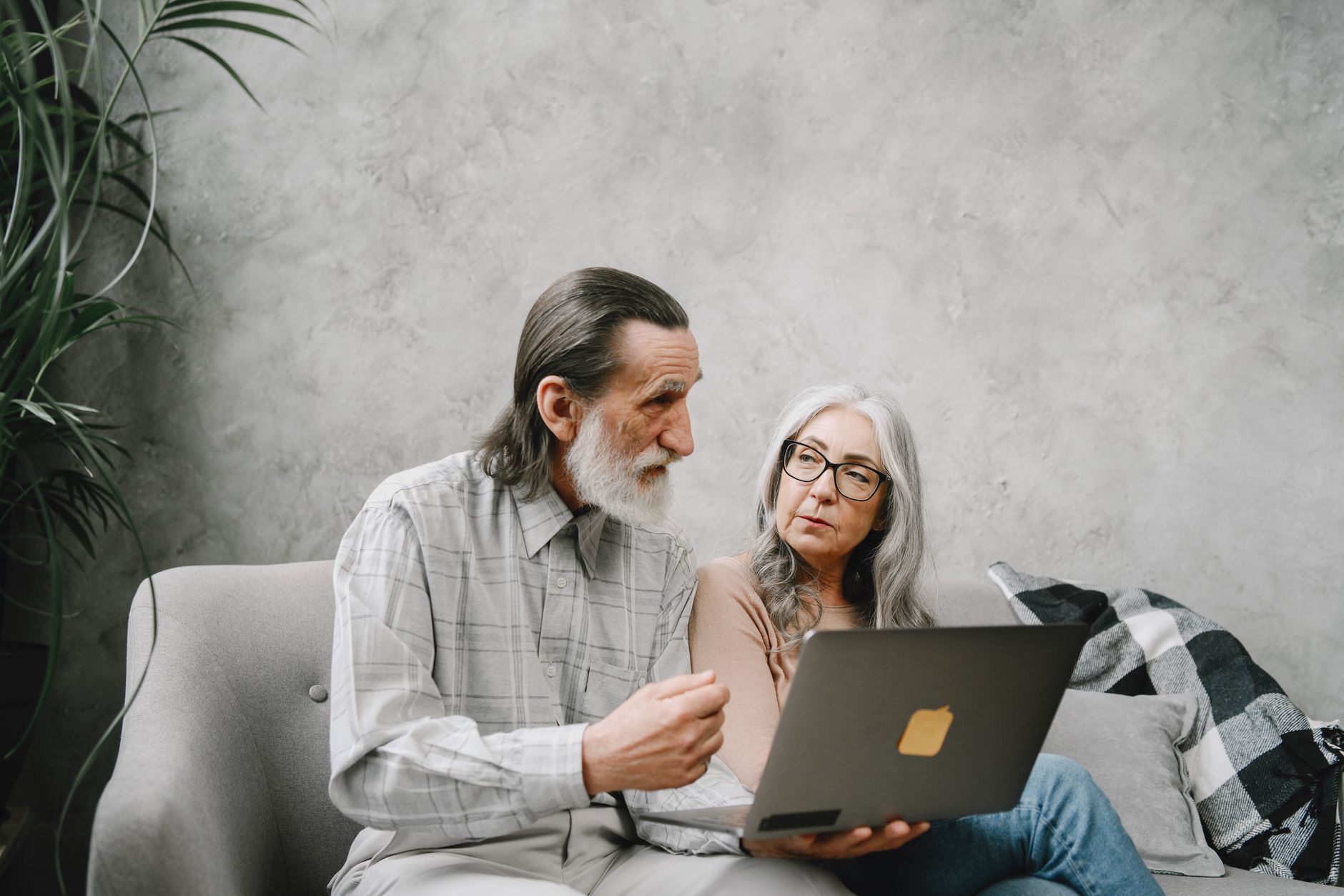 an adult child helping an older parent with a laptop in a bright living room