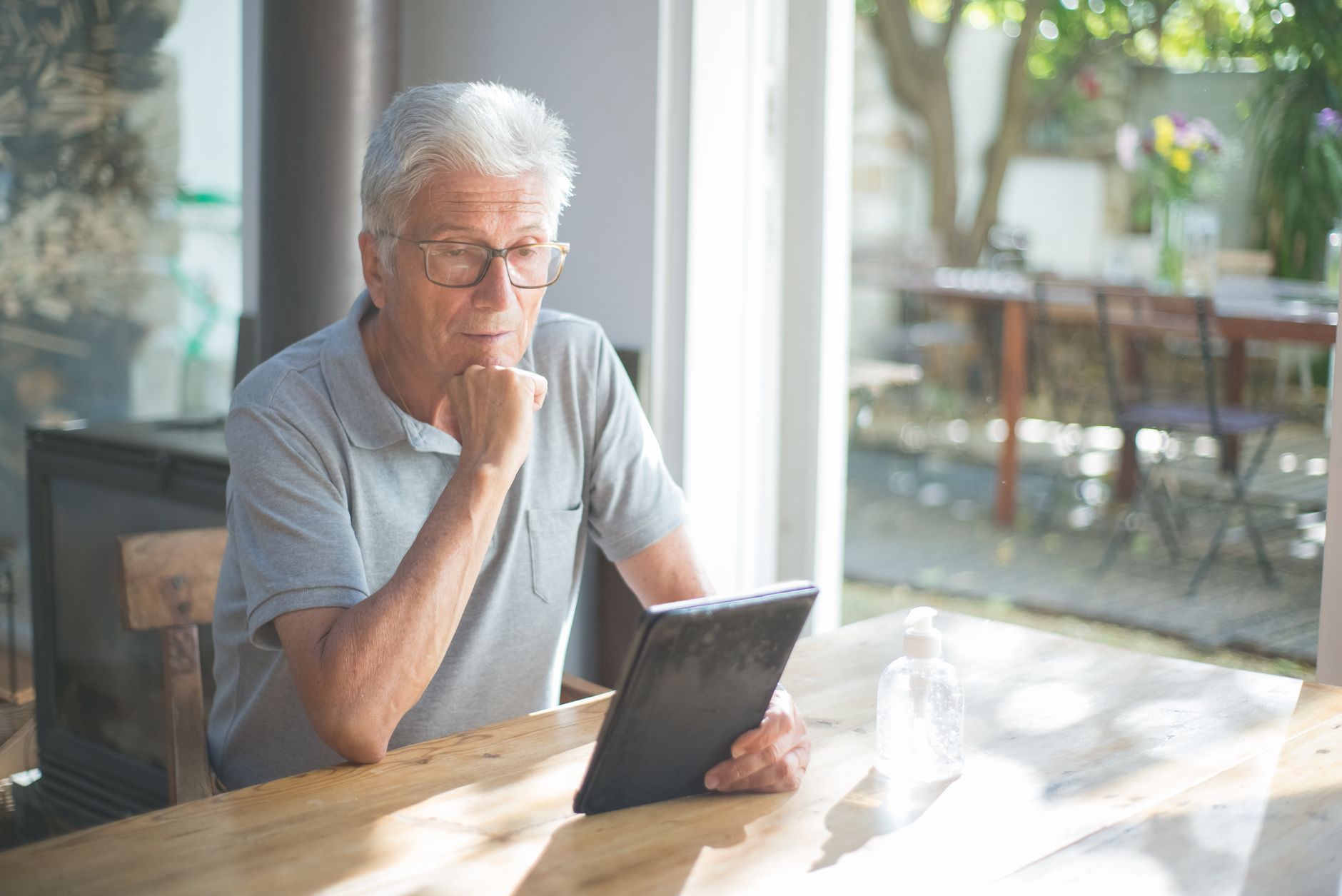 an older adult using a tablet with a worried expression while sitting on a couch