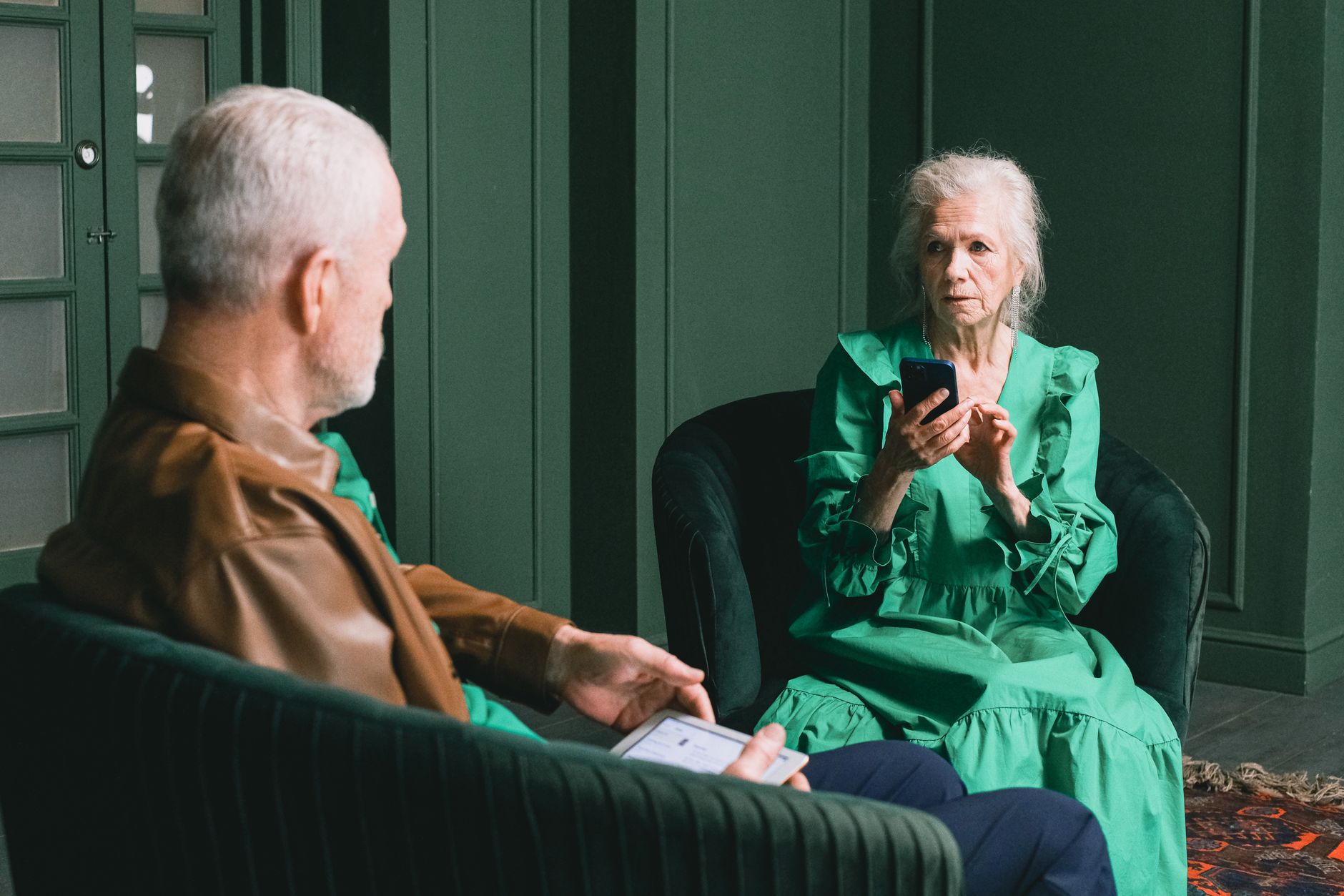 An older adult holding a smartphone, taking a screenshot of a suspicious message in a living room